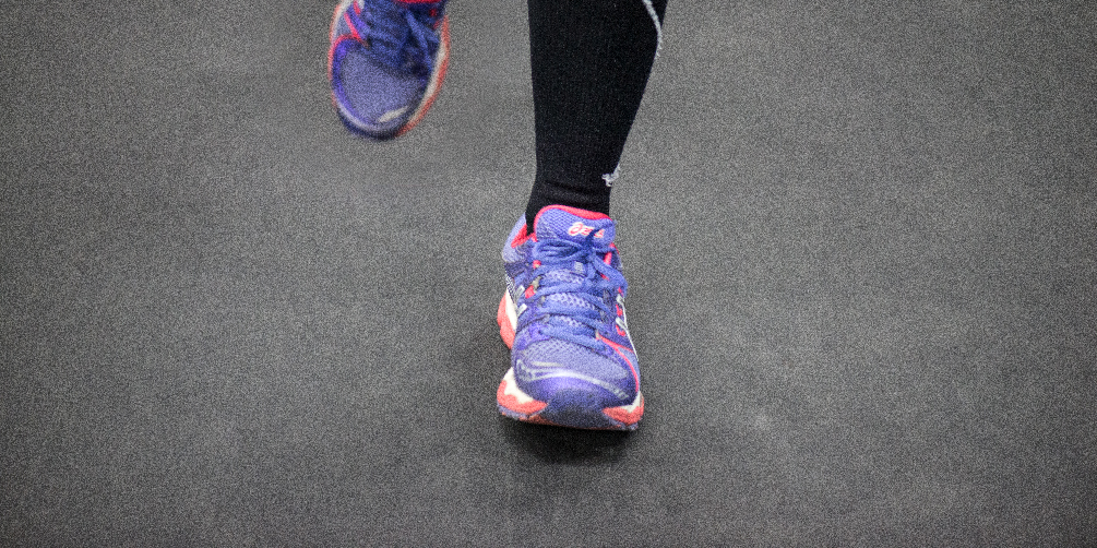 Juoksijan jalka näkyen vain säärestä alaspäin. Jalassa mustat trikoot ja puna-violetin väriset lenkkarit.